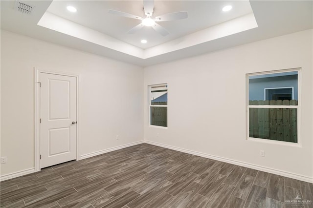 empty room featuring ceiling fan, recessed lighting, dark wood finished floors, baseboards, and a raised ceiling