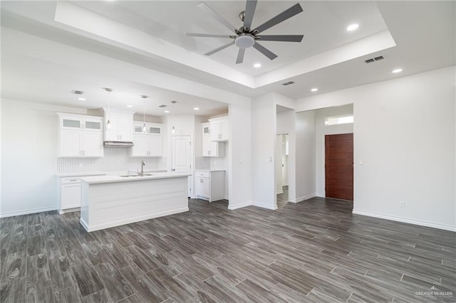 kitchen featuring visible vents, a raised ceiling, open floor plan, dark wood-style flooring, and a sink