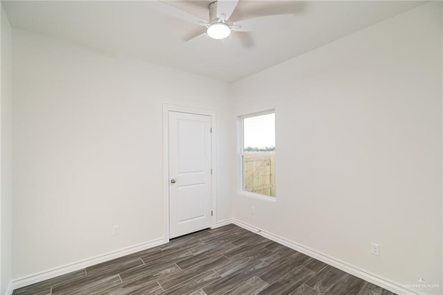 spare room featuring a ceiling fan, dark wood-style flooring, and baseboards