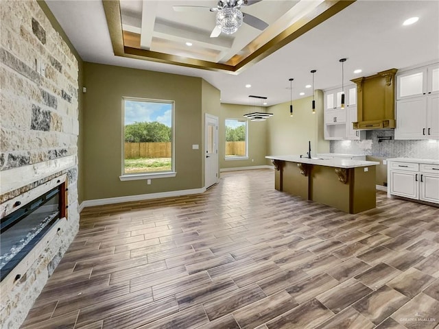 kitchen with a kitchen breakfast bar, a center island with sink, white cabinetry, and hardwood / wood-style flooring