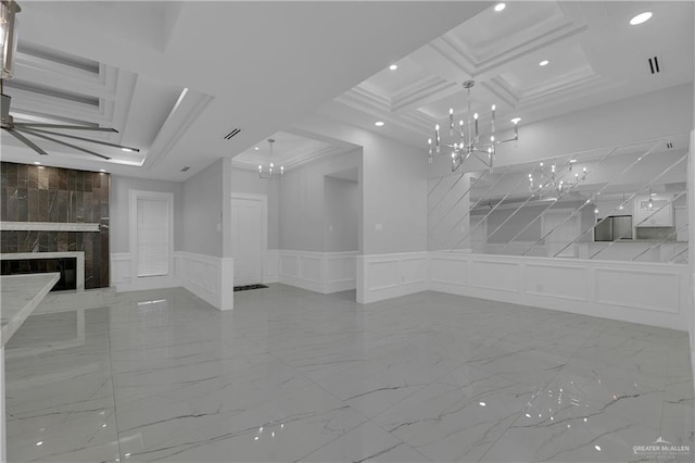 spare room with coffered ceiling, crown molding, a tile fireplace, a notable chandelier, and beamed ceiling