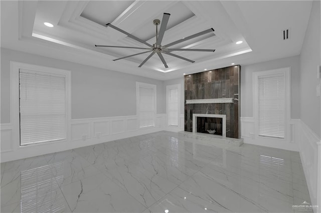 unfurnished living room featuring ceiling fan, a large fireplace, and a raised ceiling