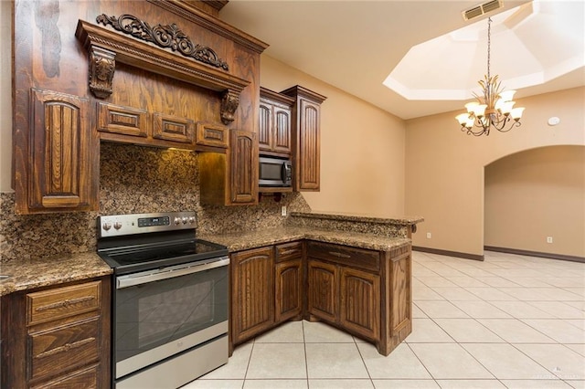 kitchen with decorative backsplash, appliances with stainless steel finishes, dark stone counters, an inviting chandelier, and light tile patterned flooring