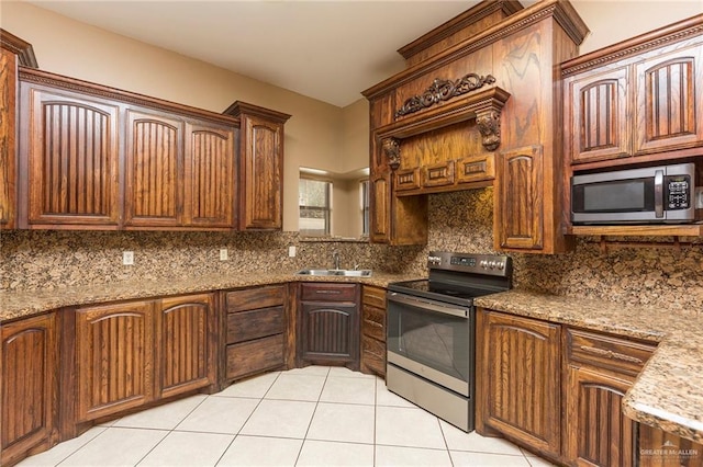 kitchen with light stone countertops, sink, stainless steel appliances, backsplash, and light tile patterned floors