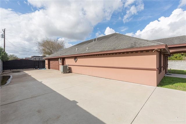 view of home's exterior featuring a shingled roof, fence, and stucco siding