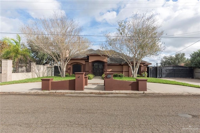 view of front of property with a gate, a fenced front yard, and stucco siding