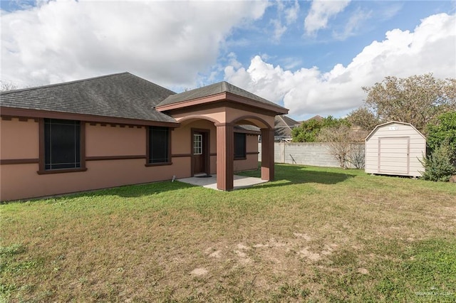 rear view of house featuring stucco siding, a lawn, fence, a shed, and an outdoor structure