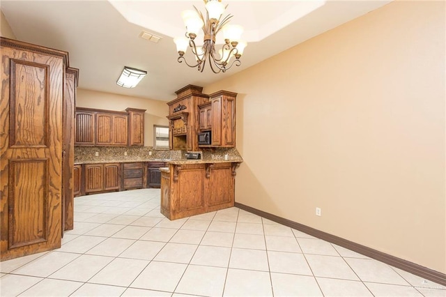 kitchen featuring kitchen peninsula, tasteful backsplash, a breakfast bar, a chandelier, and hanging light fixtures