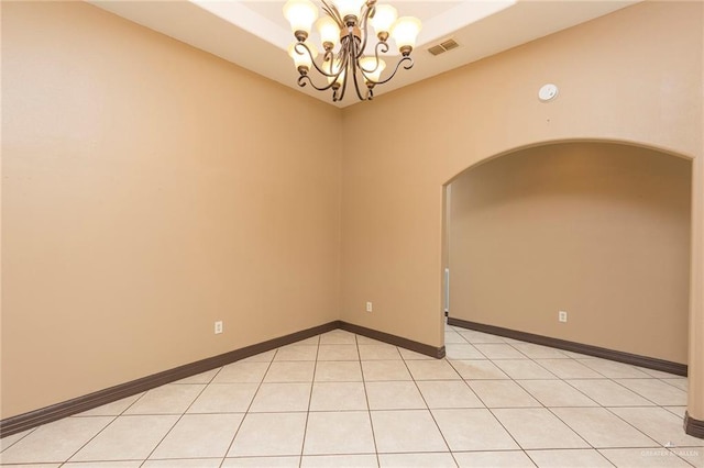 empty room with visible vents, baseboards, a notable chandelier, and arched walkways