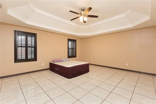 unfurnished room with a tray ceiling, ceiling fan, and light tile patterned flooring