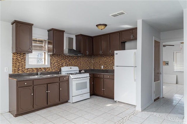 kitchen with wall chimney exhaust hood, white appliances, dark countertops, and a sink