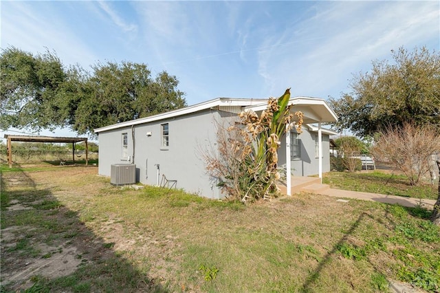 view of property exterior with a carport, cooling unit, a lawn, and stucco siding