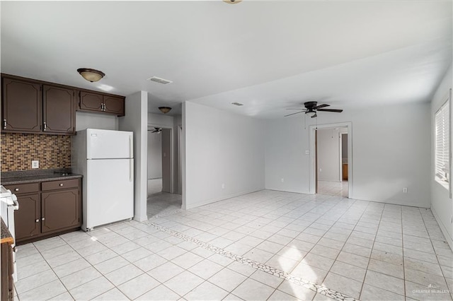 kitchen with dark brown cabinetry, tasteful backsplash, visible vents, a ceiling fan, and freestanding refrigerator