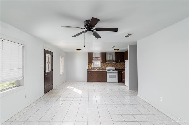 kitchen with tasteful backsplash, visible vents, dark brown cabinets, wall chimney range hood, and gas range gas stove