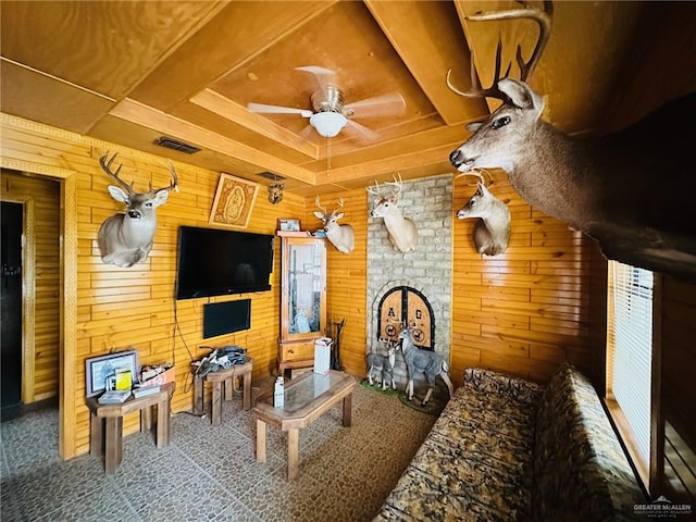 living room featuring a fireplace, ceiling fan, and wood walls