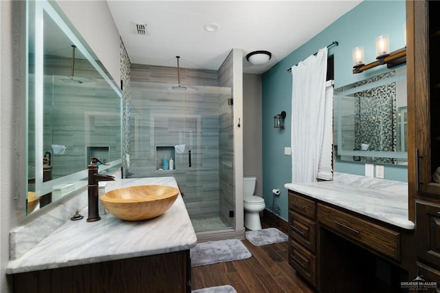 bathroom featuring a shower with door, vanity, and toilet