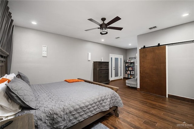 bedroom with ceiling fan, a barn door, and dark wood-type flooring