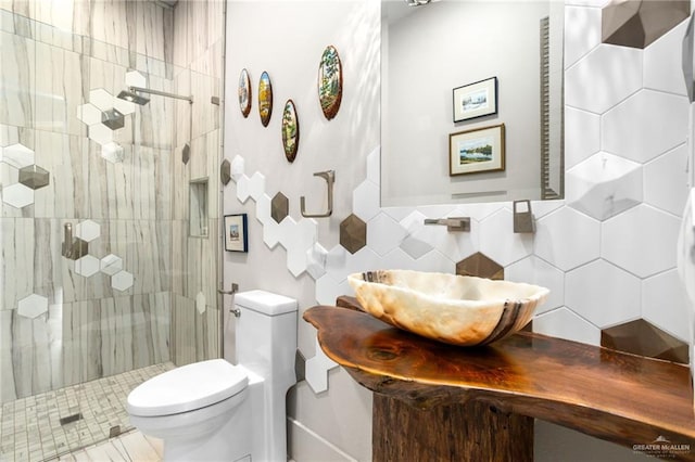 bathroom with sink, walk in shower, toilet, decorative backsplash, and tile walls