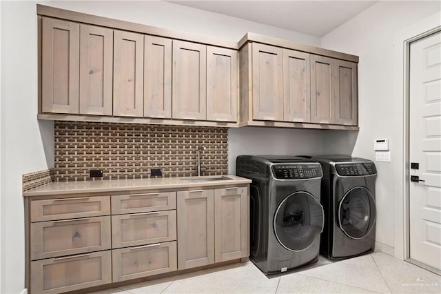 washroom with cabinets, light tile patterned flooring, washer and dryer, and sink