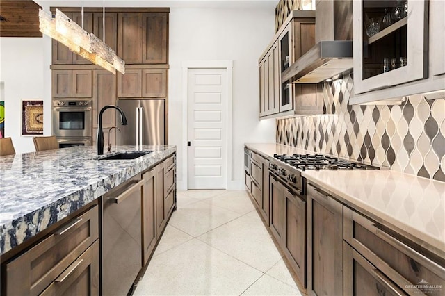 kitchen featuring sink, stainless steel appliances, wall chimney range hood, backsplash, and pendant lighting