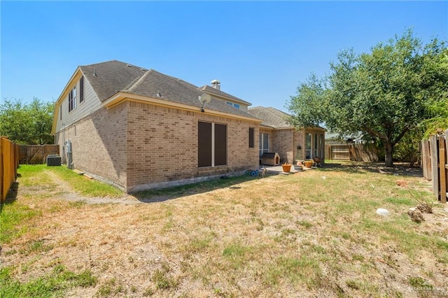 rear view of property featuring central AC unit, a yard, and a patio