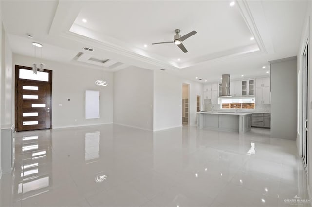 unfurnished living room featuring a ceiling fan, visible vents, light tile patterned floors, a tray ceiling, and recessed lighting