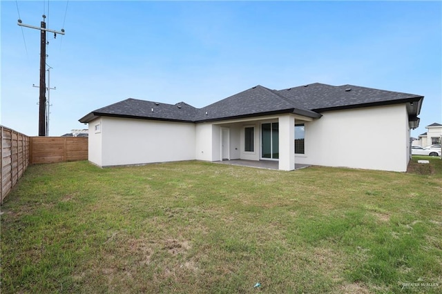 back of property with a fenced backyard, stucco siding, and a lawn