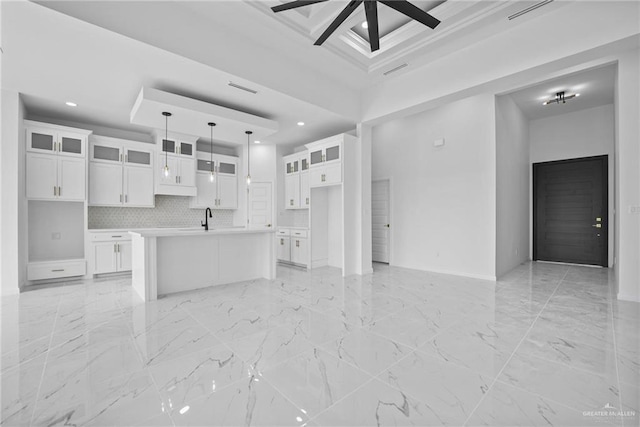 kitchen with open floor plan, white cabinetry, and an island with sink