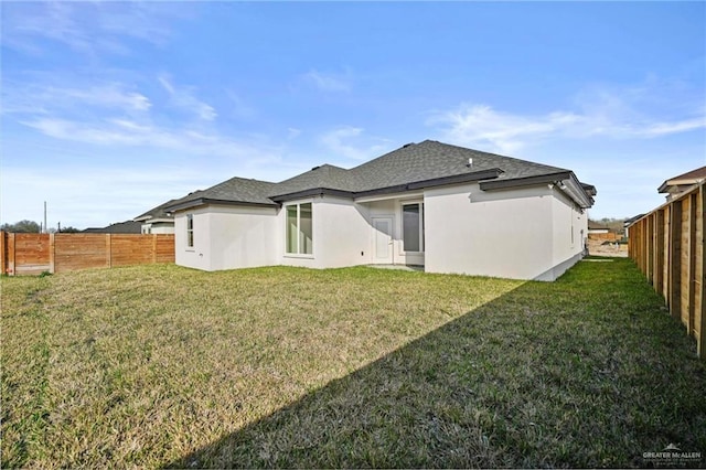 rear view of property featuring a fenced backyard, a lawn, and stucco siding