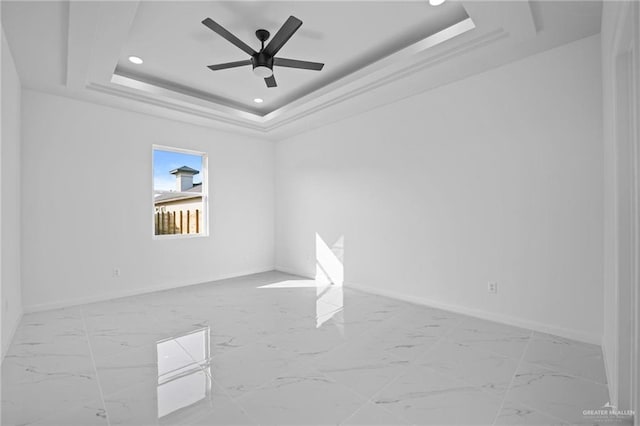 spare room with baseboards, ceiling fan, marble finish floor, a tray ceiling, and recessed lighting