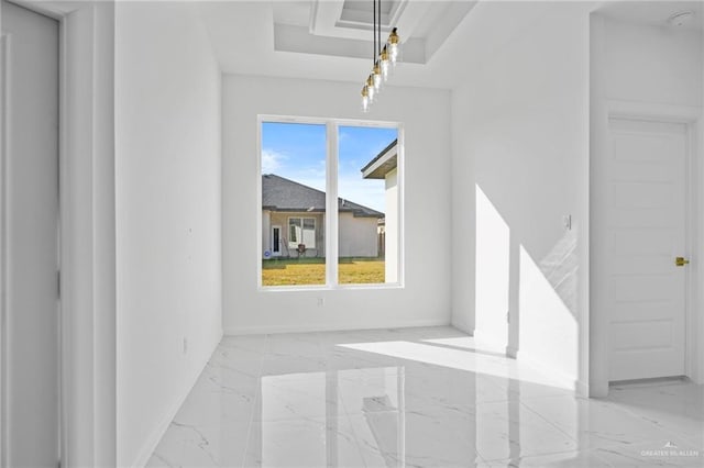 interior space featuring a tray ceiling, marble finish floor, and baseboards