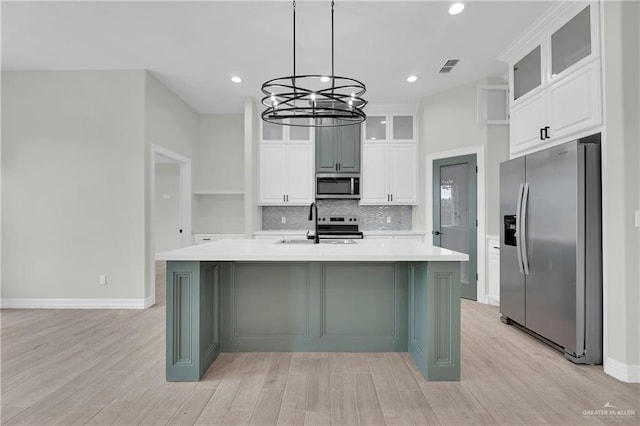 kitchen featuring light wood finished floors, tasteful backsplash, stainless steel appliances, and light countertops