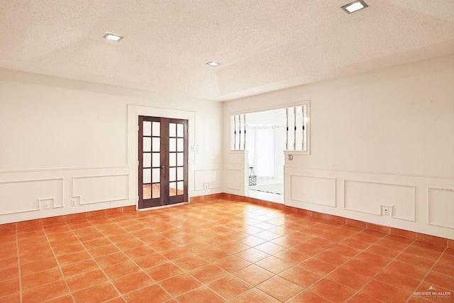 3208 Kiwi Ave, Mcallen, TX 78504 - empty room featuring a decorative wall, a textured ceiling, tile patterned floors, a wainscoted wall, and french doors