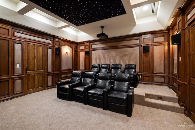 cinema featuring a tray ceiling and light colored carpet