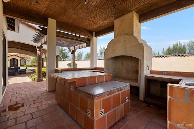 view of patio / terrace featuring an outdoor kitchen, a large fireplace, and a pergola