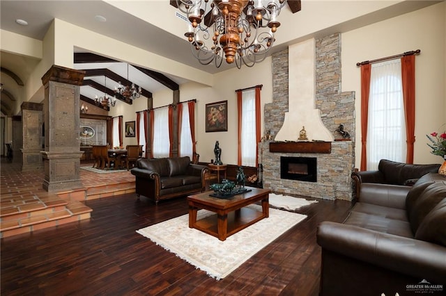 living room with high vaulted ceiling, hardwood / wood-style flooring, a fireplace, a notable chandelier, and decorative columns