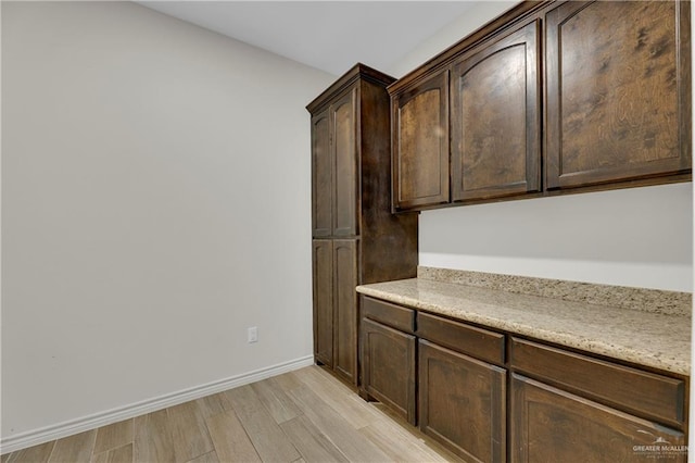 kitchen with dark brown cabinetry and light hardwood / wood-style flooring