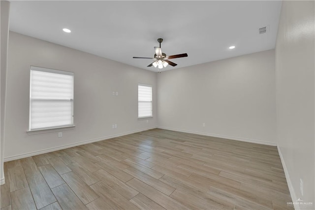 spare room with baseboards, visible vents, ceiling fan, and light wood finished floors