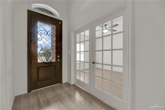 doorway with french doors, a ceiling fan, light wood-style flooring, and baseboards