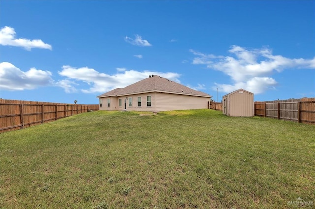 rear view of house featuring an outbuilding, a storage unit, a lawn, and a fenced backyard