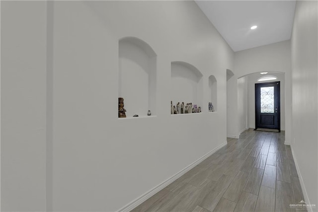 entrance foyer featuring baseboards, arched walkways, and light wood-style floors