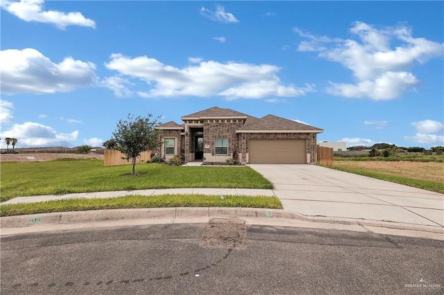 prairie-style home featuring concrete driveway, an attached garage, fence, a front yard, and brick siding