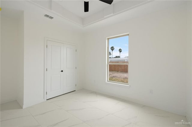 unfurnished bedroom with visible vents, baseboards, a ceiling fan, marble finish floor, and a closet