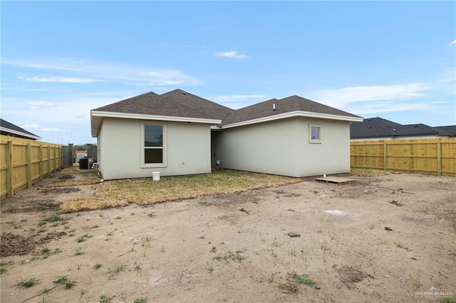 back of property featuring a fenced backyard, a shingled roof, and stucco siding