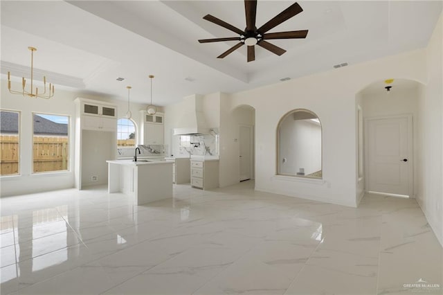 unfurnished room with ceiling fan, a high ceiling, visible vents, marble finish floor, and a tray ceiling