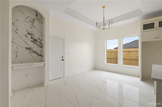 unfurnished dining area featuring baseboards, marble finish floor, a raised ceiling, and an inviting chandelier