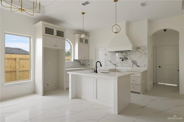 kitchen with light countertops, hanging light fixtures, a sink, and glass insert cabinets