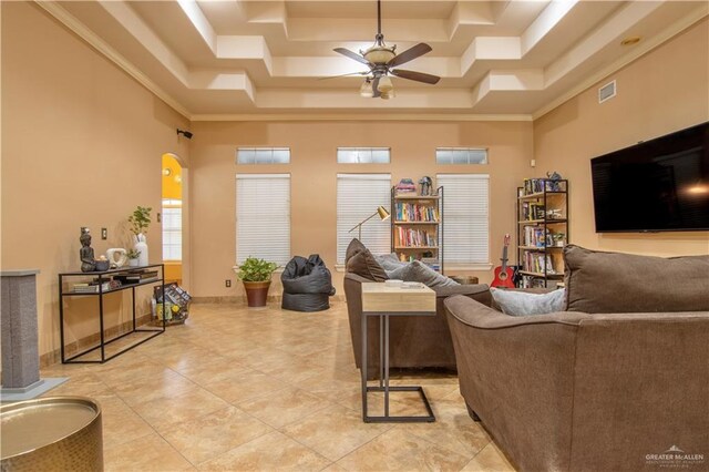 living room with a towering ceiling, a tray ceiling, ceiling fan, and ornamental molding