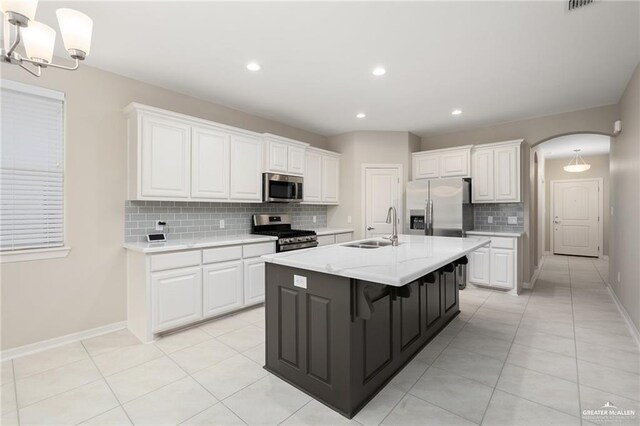 kitchen with sink, a breakfast bar, appliances with stainless steel finishes, white cabinets, and a center island with sink