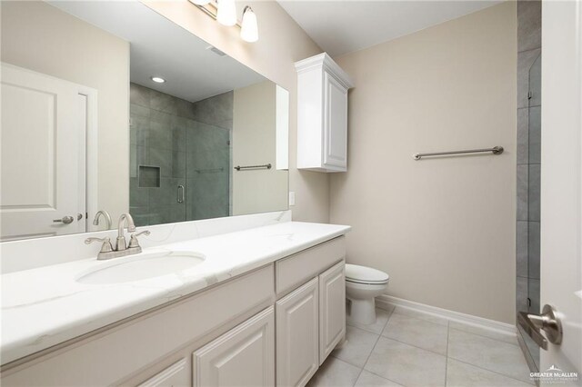 bathroom featuring tile patterned flooring, vanity, a shower with shower door, and toilet